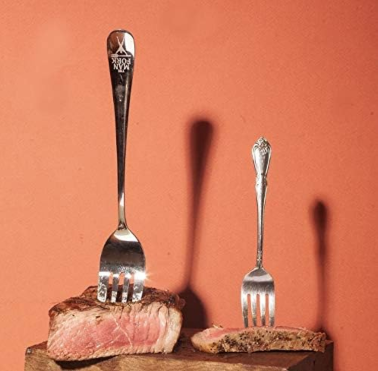 The Man Fork staged in a steak next to a regular fork